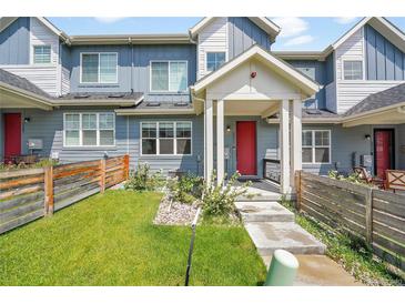 Charming townhome featuring a red front door, covered porch, and small front yard with wooden fence at 6211 W 28Th Ct, Wheat Ridge, CO 80214
