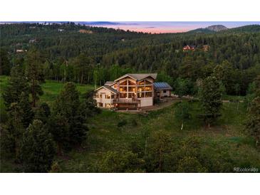Stunning mountain home with expansive windows and lush greenery at 28532 Hummingbird Hill Rd, Conifer, CO 80433