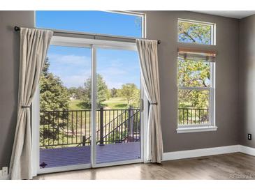 Bright living area with sliding glass doors leading to a deck with golf course views and ample natural light at 8922 S Tuscany Ln, Highlands Ranch, CO 80130