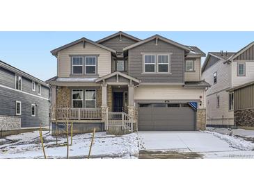 Charming two-story home featuring a stone facade, welcoming front porch, and attached two-car garage at 585 Twilight St, Erie, CO 80516