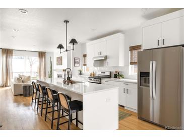 Modern kitchen with a center island, breakfast bar, stainless steel appliances, and bright living area at 3422 S Grant St, Englewood, CO 80113