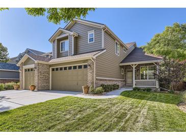 Charming two-story home featuring a well-manicured lawn, brick accents, and an inviting covered porch at 3080 Madison Ln, Broomfield, CO 80023