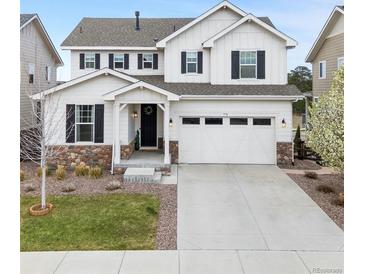 Charming two-story home with a white exterior, stone accents, a two-car garage, and manicured landscaping at 7756 S Eaton Park Ct, Aurora, CO 80016