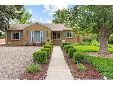Charming brick home featuring lush landscaping, inviting walkway, and mature shade trees at 2690 Magnolia St, Denver, CO 80207
