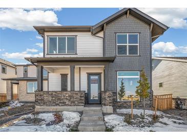 Charming two-story home featuring a stone facade, covered porch, and neutral color palette at 21234 E 63Rd Dr, Aurora, CO 80019