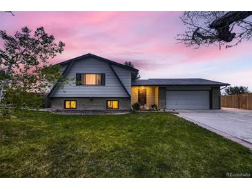 Charming two-story home with landscaped lawn, covered porch, and attached two-car garage at dusk at 1062 Jasper St, Aurora, CO 80011