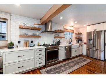 Modern kitchen with white cabinets, stainless steel appliances, open shelving, and hardwood floors at 6361 S Spotswood Cir, Littleton, CO 80120