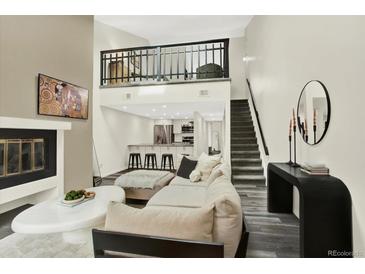 Bright living room boasts hardwood floors, fireplace, loft, and staircase to the upper level at 8055 E Colorado Ave # 8, Denver, CO 80231