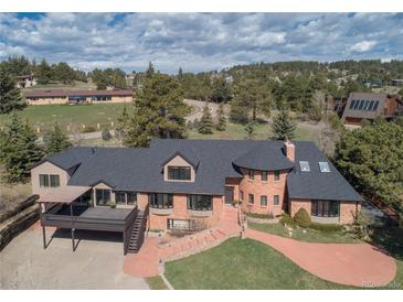 Stunning brick home featuring a spacious deck, curved entry, and lush landscaping at 22081 Paradise Cir, Golden, CO 80401