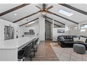 Open-concept living room features vaulted ceilings, exposed beams, and seamless flow into a modern kitchen at 9630 N Surrey Dr, Castle Rock, CO 80108