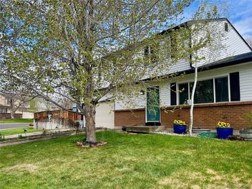 Charming two-story home with green lawn, brick accents, attached garage, and beautiful trees at 4934 S Flower Way, Littleton, CO 80123