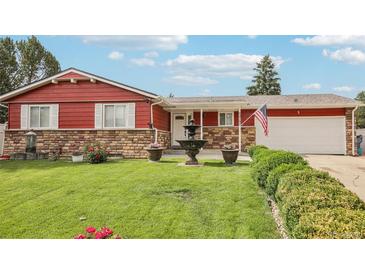Charming red single-story home featuring a well-manicured lawn, stone accents, and a decorative water fountain at 14791 E Security Pl, Aurora, CO 80011