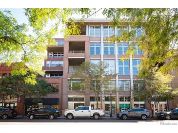 Modern multi-story condo building featuring large windows and balconies, surrounded by lush green trees and sidewalks at 1720 Wazee St # 3B, Denver, CO 80202