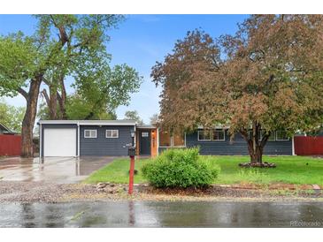 Charming single-story home featuring a lush front yard and attached garage, freshly painted with modern colors at 4405 Gardenia St, Golden, CO 80403