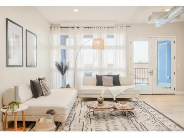 Bright living room features stylish sectional sofa and large windows at 3198 Blake St # 402, Denver, CO 80205