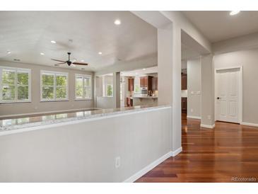 Bright living room featuring hardwood floors, natural light, and open floor plan to kitchen and adjacent rooms at 2485 Vale Way, Erie, CO 80516