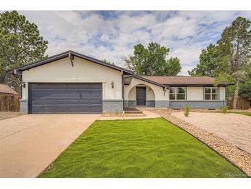 Charming home featuring a well-maintained lawn, complemented by tasteful rock landscaping and a painted two-car garage door at 1819 S Nile Ct, Aurora, CO 80012