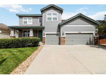Charming two-story home with a well-manicured lawn, two-car garage and appealing gray siding with stone accents at 10730 Hillrose St, Parker, CO 80134