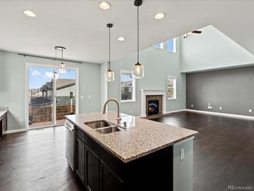 Open-concept kitchen with granite countertops, stainless steel appliances, and a cozy fireplace at 10730 Hillrose St, Parker, CO 80134