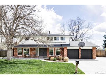 Charming two-story home featuring a red brick exterior, large front yard, and an attached two-car garage at 7060 S Windsor St, Littleton, CO 80128