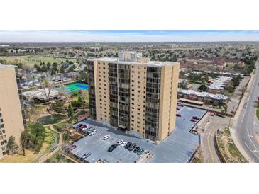 An exterior view of a modern high-rise condominium complex with a parking area and green spaces at 7877 E Mississippi Ave # 607, Denver, CO 80247