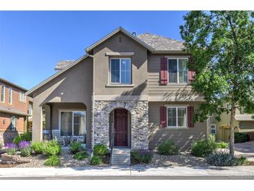 Charming two-story home featuring a stone-accented entrance and covered patio, surrounded by lush landscaping at 10550 Ashfield St, Highlands Ranch, CO 80126