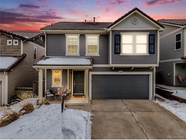 Charming two-story home with gray siding, a two-car garage, and a cozy covered front porch at 2418 Coach House Loop, Castle Rock, CO 80109