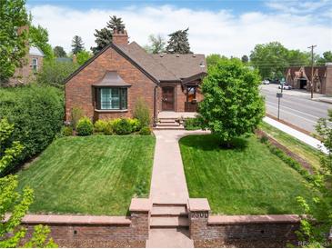 Charming brick home with a well-manicured lawn and a stone walkway leading to the entrance at 2300 Jasmine St, Denver, CO 80207
