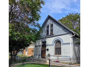 Charming home featuring unique architectural details, light grey brick, and a well-maintained front yard with trees at 4316 Josephine St, Denver, CO 80216