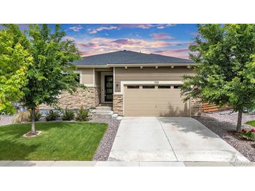 Charming single-story home with a stone facade, well-manicured lawn, and attached two-car garage at 722 Eva Peak Dr, Erie, CO 80516