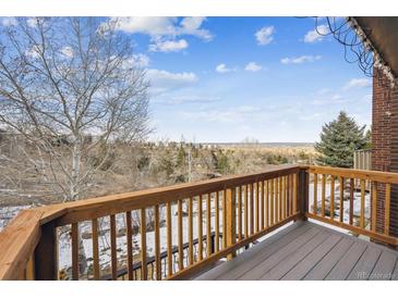 View of a deck with wooden railings and a nice view of nature and bare trees on a partially cloudy day at 148 S Holman Way, Golden, CO 80401