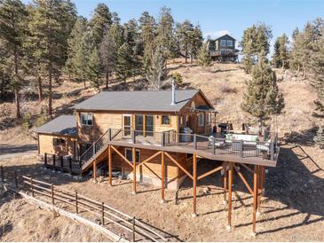 Hillside house with wood siding, a spacious deck and lovely mountain views at 10180 Blue Sky Trl, Conifer, CO 80433