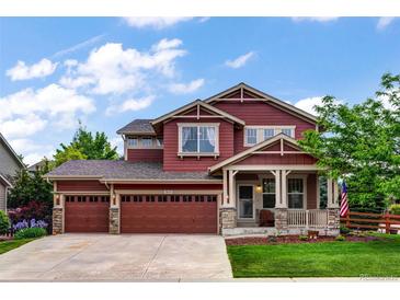 Charming two-story home with a three-car garage, well-manicured lawn, and inviting front porch at 10614 Kicking Horse Dr, Littleton, CO 80125