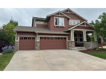 Two-story house featuring a three-car garage and a covered porch with stone accents at 10614 Kicking Horse Dr, Littleton, CO 80125