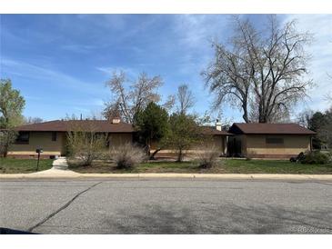 Charming single-story home featuring a brick exterior, mature trees, and a well-maintained front yard at 5600 Dover St, Arvada, CO 80002
