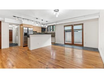 Open-concept living room and kitchen with hardwood floors and natural light from the double doors to the outside at 2533 E 11Th Ave # 1, Denver, CO 80206