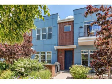 Contemporary blue townhouse with brick accents, a small balcony, and lush landscaping creating inviting curb appeal at 2346 Central Park Blvd, Denver, CO 80238