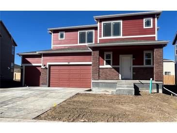 Two-story home featuring a two-car garage, covered porch with brick accents, and a traditional front door at 747 Sunflower Dr, Brighton, CO 80601