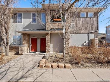 Stylish townhome featuring a stone facade, bright red doors, and modern architectural details at 9300 E Florida Ave # 1001, Denver, CO 80247