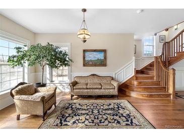 Elegant living room featuring hardwood floors, a decorative rug, staircase, and a large window at 7996 Bradburn Blvd, Westminster, CO 80030