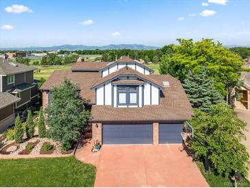 Charming two-story home with a three-car garage, lush landscaping, and mountain views in the background at 1175 Oakhurst Dr, Broomfield, CO 80020