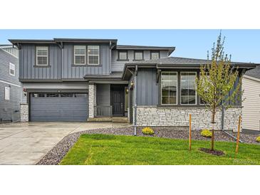 Charming two-story home with gray siding, stone accents, manicured lawn, and attached two car garage at 630 Sunrise St, Erie, CO 80516