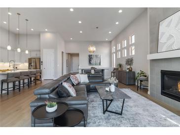 Spacious living room featuring a fireplace, modern decor, and an open floor plan connecting to the kitchen at 1588 Blackwood Ct, Erie, CO 80516