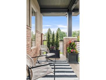 Inviting front porch with stylish furniture, planters, and a striped rug at 6485 E Cedar Ave, Denver, CO 80224