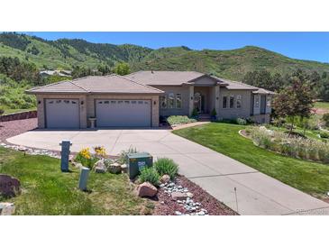 Beautiful single-story home featuring a three-car garage, lush green lawn, and mountain views at 10950 Elk Horn Run, Littleton, CO 80125