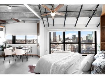 Bright bedroom boasts a modern ceiling fan, white bedding and a large window with fantastic city views at 100 Park W Ave # 2008, Denver, CO 80205