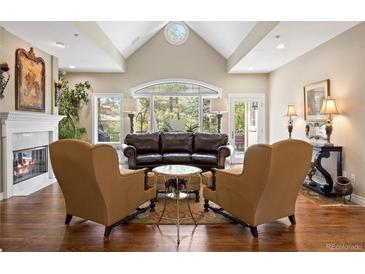 Elegant living room features vaulted ceilings, fireplace, hardwood floors, and a wall of windows with natural light at 315 Prospect Dr, Castle Rock, CO 80108