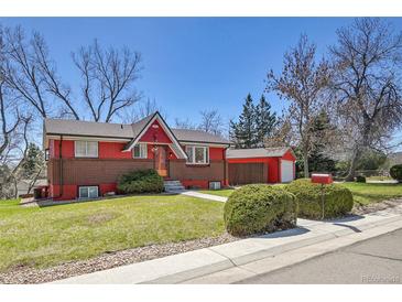 Charming red and brick home with lush green lawn and mature trees on a sunny day at 10978 W Ada Pl, Lakewood, CO 80226