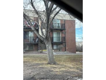 Brick apartment building featuring balconies on each level near a big tree at 5995 W Hampden Ave # 23, Denver, CO 80227