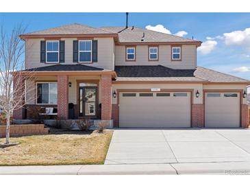 Two-story home boasts a three car garage, brick accents, neutral color, and well-manicured lawn at 1301 Sidewinder Cir, Castle Rock, CO 80108